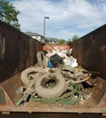 Muddy Trash in a Dumpster Collected During a Cleanup Event, Tires Covered in Mud