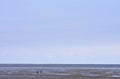 Mudflat walking couple in dutch Waddensea, Moddergat