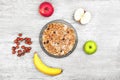 Muesli with banana, apple and nuts. Bowl of porridge with fruits and milk on the wooden gray background. Wholesome breakfast.