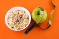 muesli with banana on orange background with apple and measuring tape Royalty Free Stock Photo