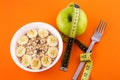 muesli with banana on orange background with apple and measuring tape Royalty Free Stock Photo