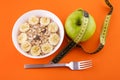 muesli with banana on orange background with apple and measuring tape Royalty Free Stock Photo