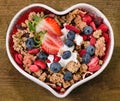 Muesli with berries and yogurt in heart shaped bowl. Royalty Free Stock Photo