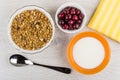 Muesli in bowl, cherry, napkin, spoon, bowl with yogurt