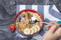 Muesli. Breakfast, healthy food and diet. Muesli with milk and fruit in a plate on a black marble top. Woman& x27;s hand with Royalty Free Stock Photo