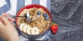 Muesli. Breakfast, healthy food and diet. Muesli with milk and fruit in a plate on a black marble top. Woman's hand with Royalty Free Stock Photo