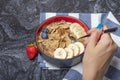 Muesli. Breakfast, healthy food and diet. Muesli with milk and fruit in a plate on a black marble top. Woman's hand with Royalty Free Stock Photo