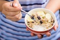 Muesli cereal in a bowl holding by hand and eating