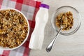 Muesli with cereals, raisin and sunflower seeds in plate on napkin, bottle of yogurt, spoon and granola in bowl on wooden table. Royalty Free Stock Photo