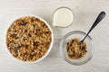 Muesli with cereals, raisin and sunflower seeds in plate, pitcher with yogurt, spoon and granola in bowl on wooden table. Top view Royalty Free Stock Photo