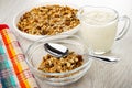 Muesli with cereals, raisin and sunflower seeds in plate, napkin, jug of yogurt, spoon and granola in bowl on wooden table Royalty Free Stock Photo