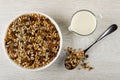 Muesli with cereals, raisin and sunflower seeds in plate, pitcher with yogurt, spoon with granola on table. Top view Royalty Free Stock Photo