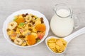 Muesli in white bowl, jug milk and spoon corn flakes