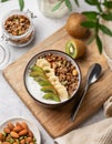 Granola with yogurt, banana and kiwi in a bowl on a light background