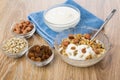 Muesli with yogurt, napkin, bowls with raisins, peanuts, sunflower seeds