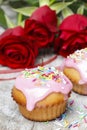 Muffins covered with pink icing and colorful sprinkles on wooden Royalty Free Stock Photo