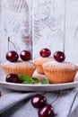 Muffins topped with cherries and sugar powder