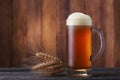 Mug of beer with wheatears on wood background