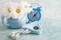 A mug, blue alarm clock and flowers