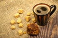 Mug with cA mug of coffee, pieces of brown cane sugar, and a cake on the wooden table. Close up.offee, cake, sugar Royalty Free Stock Photo