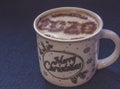 Mug of cappuccino with cinnamon on a dark blue background.Cinnamon powder was sprinkled with 2020 figures on coffee foam.