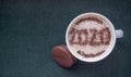 Mug of cappuccino with cinnamon on a dark cyanic background.Cinnamon powder was sprinkled with 2020 figures on coffee foam.