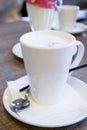 A mug of cappuccino is closed up, decorated on top of the foam on the table in the cafe