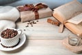 A mug with coffee beans, a gift box, a book, a sweater on a wooden table, with space for copying.