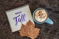 Mug of coffee, cocoa or hot chocolate with whipped cream and cinnamon on knitted scarf, leaf. sign Hello, Fall. Pumpkin Royalty Free Stock Photo