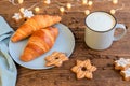 A mug of coffee with milk and foam, latte, cappuccino on a wooden table next to a fresh croissant and New Year`s garlands. Festiv