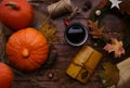 A mug of coffee stands on a wooden table and a number of orange pumpkins