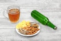 Mug of cold beer, bottle and snacks on the light wooden background. Chips, croutons, salted fish and peanuts. Royalty Free Stock Photo