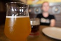 Mug of cold beer with misted glass.  Girl in blur on background Royalty Free Stock Photo