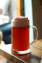 Mug of sweet cold light beer with pomegranate juice and foam on the restaurant table. Real life photography at a restaurant, sunny Royalty Free Stock Photo