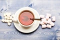 Mug filled with black brewed tea, spoon and heap of marshmallow and refined sugar on blue wooden background. Mug with Royalty Free Stock Photo