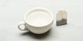 Mug filled with boiling water and teabag on white background. Tea time concept. Cup or white porcelain mug with