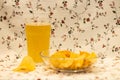 Mug of Fresh Beer and bowl of with Pile potato chips on flower background Royalty Free Stock Photo