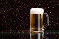 Mug fresh beer with cap of foam on colored light Royalty Free Stock Photo