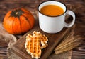 Mug of fresh pumpkin juice with wafer and pumpkin on dark wooden Royalty Free Stock Photo
