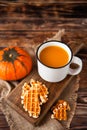 Mug of fresh pumpkin juice with wafer and pumpkin on dark wooden Royalty Free Stock Photo