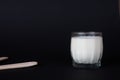 Mug of fresh steamed milk in a transparent glass glass on a black background.