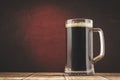 Mug full of beer on a red light background/mug full of beer on a wooden table and a red background, selective focus and copy space Royalty Free Stock Photo