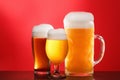 Mug and glass of beer close-up with froth over red background Royalty Free Stock Photo