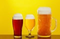 Mug and glass of beer close-up with froth over yellow background Royalty Free Stock Photo