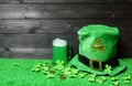 Mug of green beer and leprehaun cap, clover leaves and coins on green grass, dark wooden planks background. Saint Patricks Day Royalty Free Stock Photo