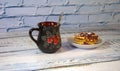 A mug of herbal tea with lemon and saucer with a stack of waffles with strawberry jam