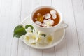 Mug of herbal tea with petals of Jasmine flowers on a light background. Royalty Free Stock Photo