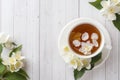 Mug of herbal tea with petals of Jasmine flowers on a light background. Royalty Free Stock Photo