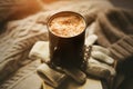 A mug of hot, aroma coffee with cream and cinnamon sprinkles sits on top of a stack of old books and white wool gloves with Royalty Free Stock Photo