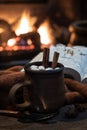 Mug of hot chocolate with fireplace burning in background